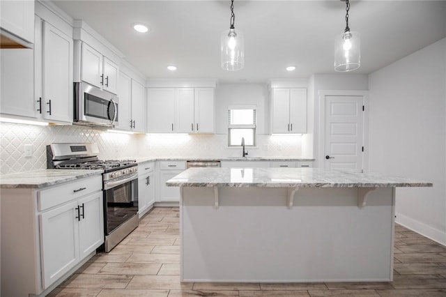 kitchen with white cabinetry, appliances with stainless steel finishes, a center island, and pendant lighting