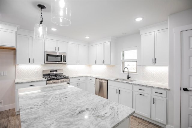 kitchen with sink, light hardwood / wood-style flooring, white cabinetry, hanging light fixtures, and stainless steel appliances