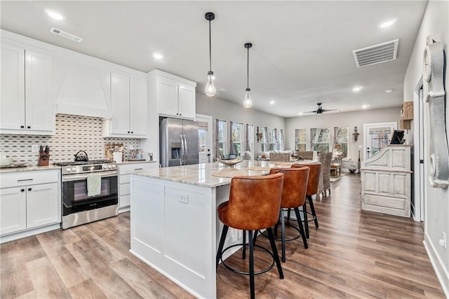 kitchen featuring custom exhaust hood, white cabinetry, a center island, pendant lighting, and stainless steel appliances