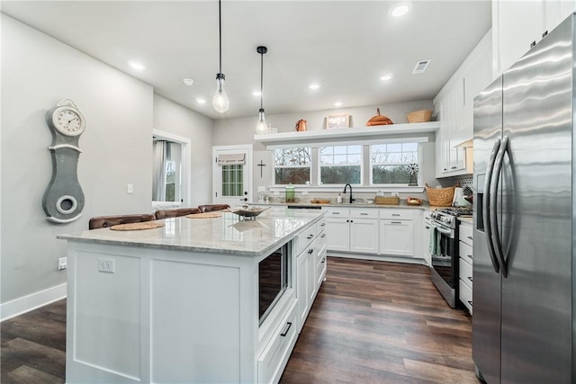 kitchen with white cabinetry, hanging light fixtures, a kitchen island, and appliances with stainless steel finishes