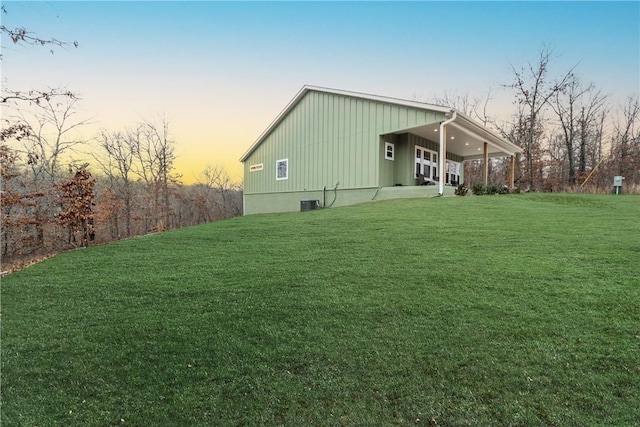 property exterior at dusk featuring a lawn