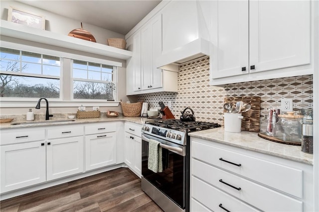 kitchen featuring sink, premium range hood, white cabinetry, stainless steel range with gas stovetop, and decorative backsplash