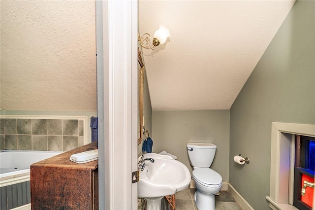 bathroom featuring a washtub, sink, a textured ceiling, vaulted ceiling, and toilet