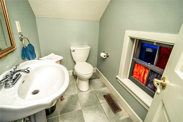 bathroom featuring sink, vaulted ceiling, toilet, and a textured ceiling