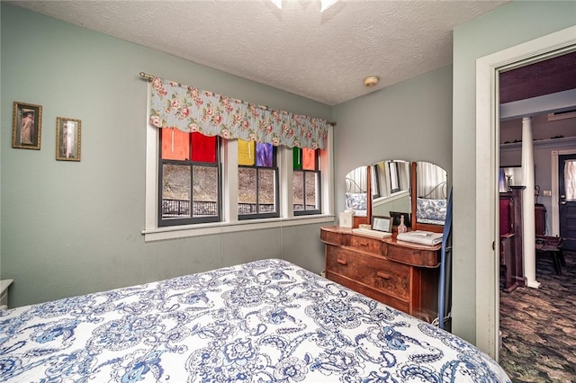 carpeted bedroom with decorative columns and a textured ceiling