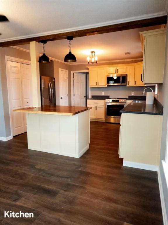 kitchen with a kitchen island, appliances with stainless steel finishes, dark wood-type flooring, decorative light fixtures, and crown molding