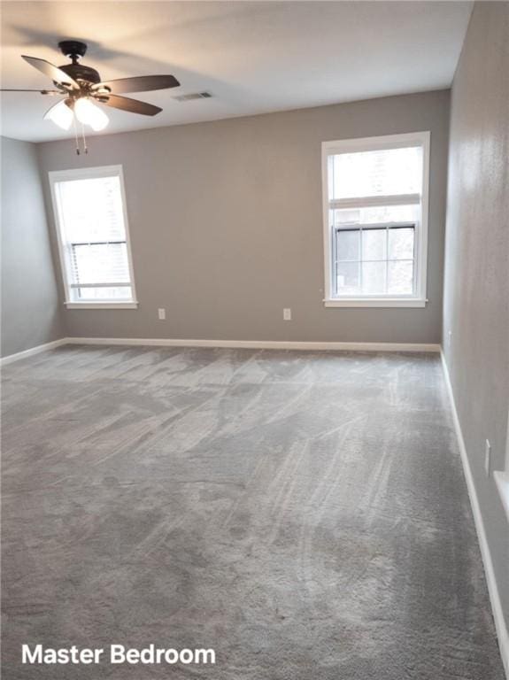 empty room with ceiling fan, carpet flooring, visible vents, and baseboards