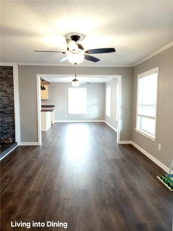 unfurnished living room featuring dark wood finished floors, crown molding, baseboards, and ceiling fan