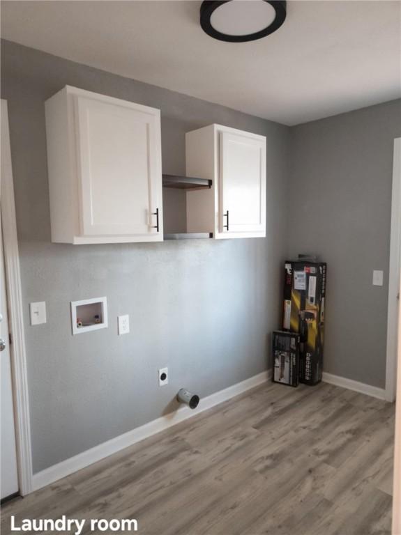 laundry area with hookup for a washing machine, electric dryer hookup, light wood-style floors, and cabinet space