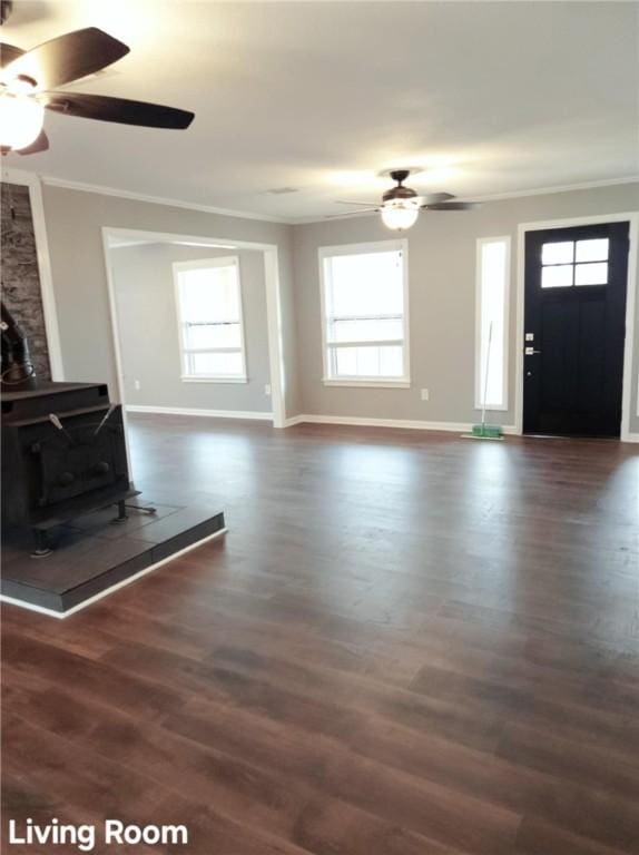 unfurnished living room with ornamental molding, dark wood finished floors, a wood stove, and ceiling fan