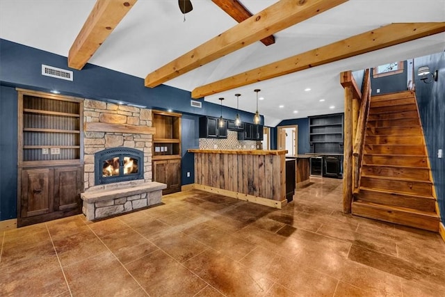 living room with vaulted ceiling with beams and a stone fireplace