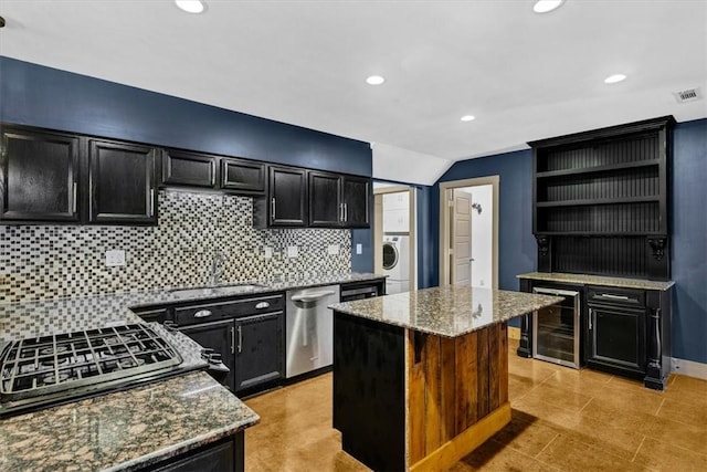 kitchen with a kitchen island, stainless steel dishwasher, wine cooler, and light stone counters