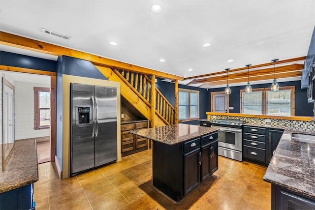 kitchen featuring sink, appliances with stainless steel finishes, hanging light fixtures, a center island, and dark stone counters