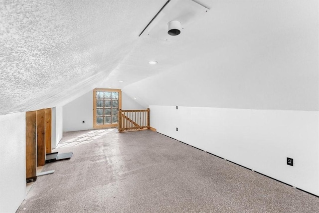 additional living space featuring lofted ceiling and a textured ceiling