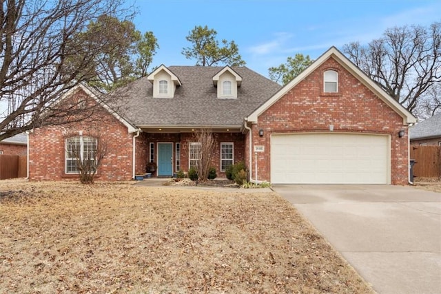 view of front facade with a garage, fence, concrete driveway, and brick siding