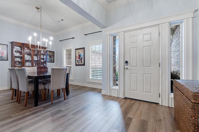 dining space with crown molding, an inviting chandelier, and light hardwood / wood-style floors