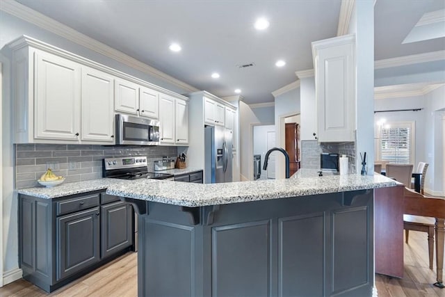 kitchen with stainless steel appliances, gray cabinetry, white cabinets, and light stone counters