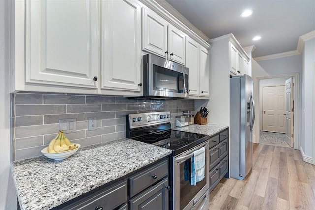 kitchen featuring white cabinetry, backsplash, ornamental molding, stainless steel appliances, and light wood-type flooring