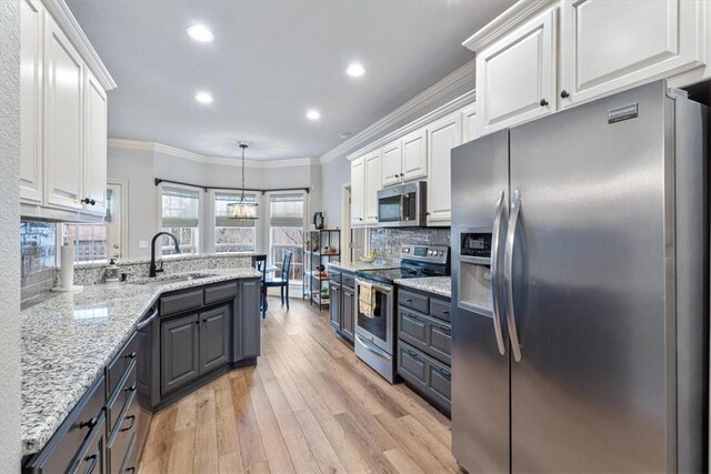 kitchen featuring appliances with stainless steel finishes, decorative light fixtures, sink, and white cabinets