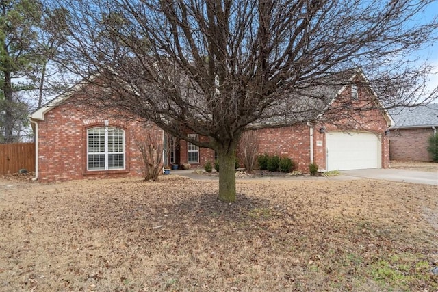 view of front of home featuring a garage, brick siding, driveway, and fence