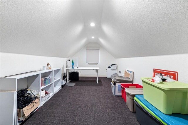 recreation room with vaulted ceiling, dark carpet, and a textured ceiling