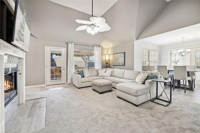 living room with ceiling fan with notable chandelier, carpet, high vaulted ceiling, and a fireplace