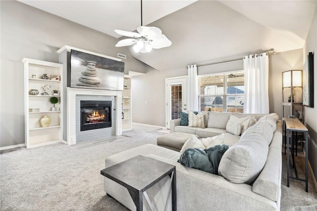 living room featuring ceiling fan, a tiled fireplace, high vaulted ceiling, and light carpet