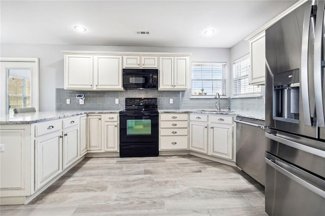 kitchen featuring tasteful backsplash, light stone countertops, kitchen peninsula, and black appliances