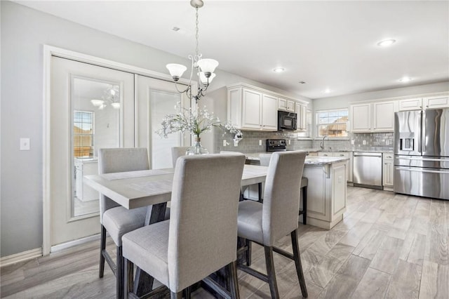 dining room with an inviting chandelier, sink, and light wood-type flooring