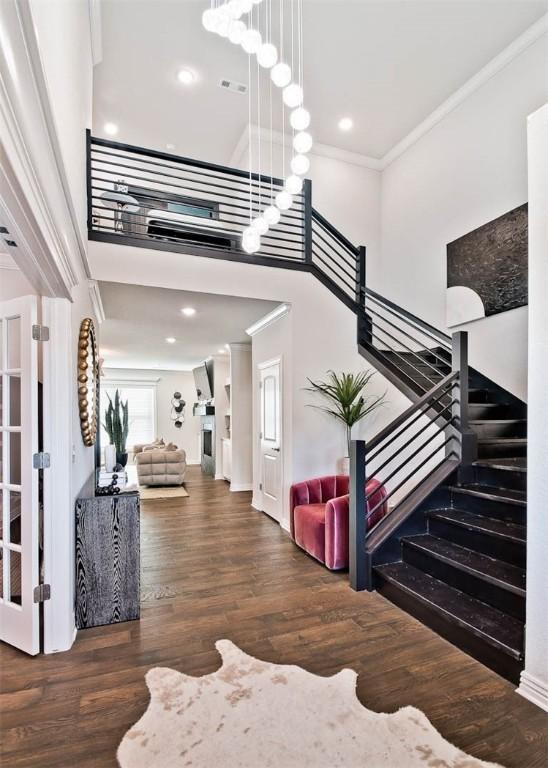 stairway featuring hardwood / wood-style floors, ornamental molding, and a high ceiling