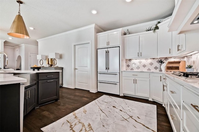 kitchen with decorative light fixtures, white cabinetry, sink, built in refrigerator, and light stone counters