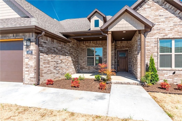 1200 Carrara St, Tontitown, AR 72762 - view of exterior entry with a shingled roof, brick siding, and an attached garage