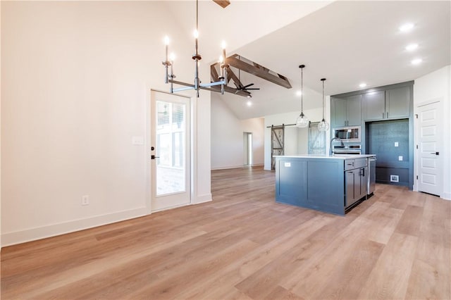 1200 Carrara St, Tontitown, AR 72762 - kitchen featuring a barn door, stainless steel microwave, a chandelier, open floor plan, and light wood-style floors