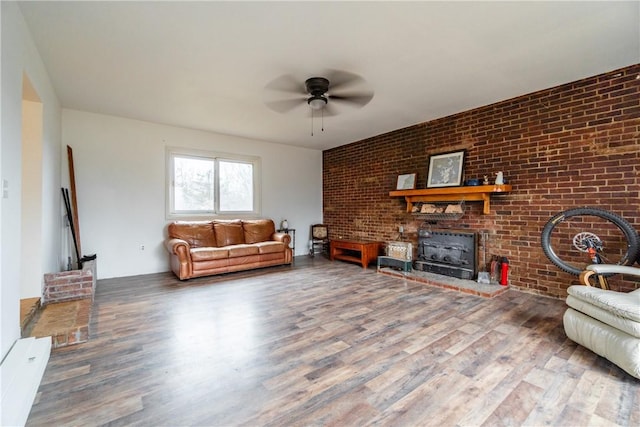 living room with a wood stove, wood finished floors, and ceiling fan