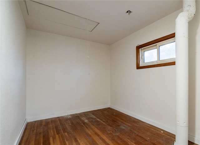 spare room featuring dark wood-type flooring, baseboards, and attic access