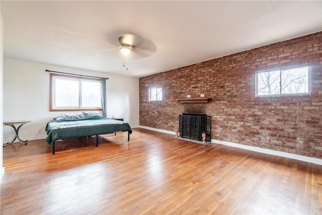 bedroom with baseboards, multiple windows, a brick fireplace, and brick wall