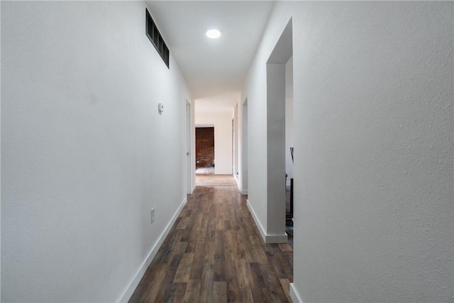 corridor featuring visible vents, baseboards, and wood finished floors