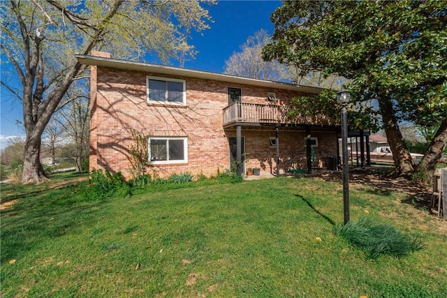 rear view of property featuring brick siding and a lawn