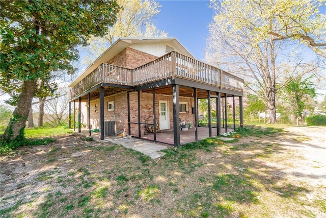 back of property with cooling unit, a patio area, a deck, and brick siding
