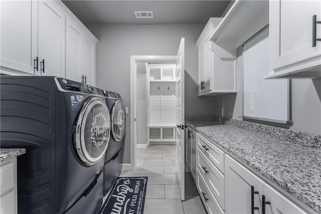 clothes washing area with cabinets, washer and clothes dryer, and light tile patterned floors