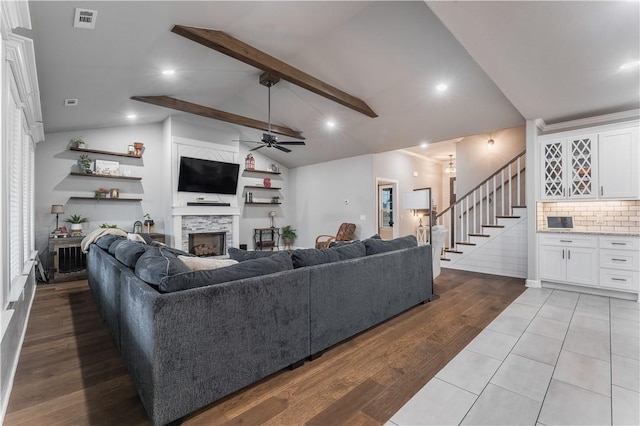 living area featuring visible vents, stairway, beam ceiling, a fireplace, and dark wood-style floors