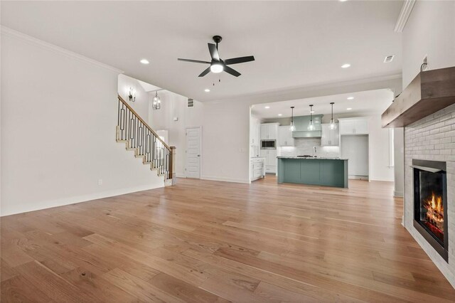 1808 Charles St, Pea Ridge, AR 72751 - unfurnished living room with a fireplace, stairs, ceiling fan, light wood-type flooring, and crown molding