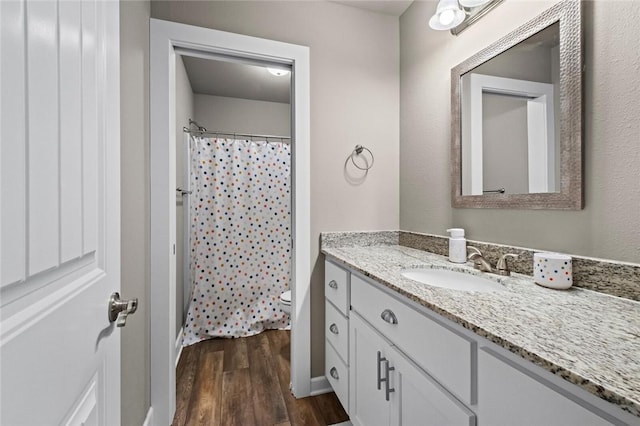 bathroom with hardwood / wood-style flooring, vanity, a shower with shower curtain, and toilet