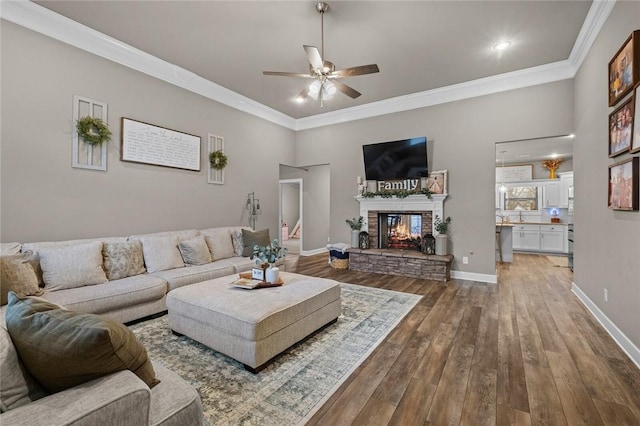 living room featuring crown molding, hardwood / wood-style flooring, a fireplace, and ceiling fan