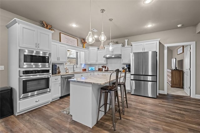 kitchen featuring appliances with stainless steel finishes, a center island, hanging light fixtures, and white cabinets