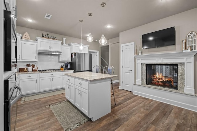 kitchen featuring white cabinetry, stainless steel appliances, hanging light fixtures, and a kitchen island