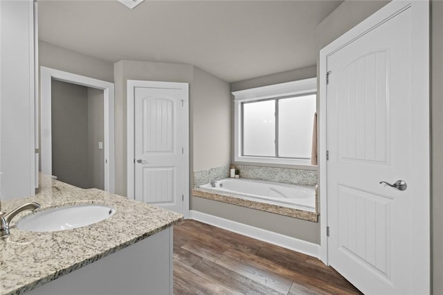 bathroom with vanity, a bath, and wood-type flooring