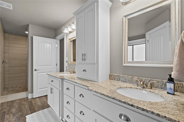 bathroom featuring vanity, wood-type flooring, and a tile shower