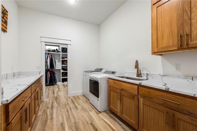 washroom with cabinets, washer and clothes dryer, sink, and light hardwood / wood-style floors