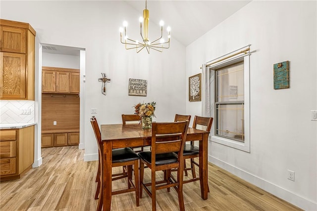 dining room with lofted ceiling, an inviting chandelier, and light wood-type flooring